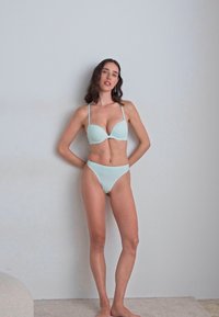 Svetlo modri bikini komplet, ki vključuje podloženo nedrček z globokim dekoltejem in nastavljivimi naramnicami ter usklajene visokotlačne hlačke, gladka tekstura, minimalistična zasnova.