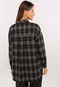 Black and gray plaid shirt with red accents, long sleeves, a collar, and a relaxed fit. Features rounded hem and a classic check pattern.