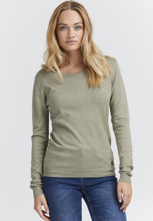 Pull vert à manches longues en maille côtelée. Présente un col rond et des poignets ajustés. Détail de logo près de l'ourlet.