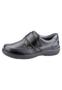 Scarpa in pelle nera con punta arrotondata, una sola ampia fascia in Velcro e suola in gomma testurizzata. Finitura liscia con dettagli di cucitura minimi.
