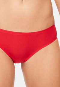 Rode bikinionder gemaakt van gladde stof, met een eenvoudig, naadloos ontwerp, een middelhoge taille en zonder zichtbare hardware of accenten.