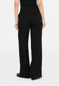 Pantaloni neri a gamba larga con una texture liscia, caratterizzati da un alto punto vita, passanti per cintura e due tasche posteriori con chiusura piatta.