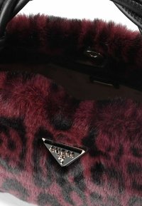 Borsa a tracolla in pelliccia sintetica bordeaux e nera con texture a stampa leopardata e placca triangolare del logo Guess, dotata di chiusura a scatto magnetico.