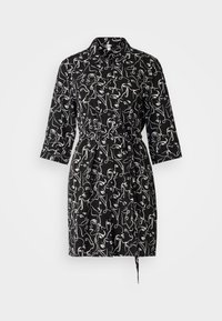 Abito camicia nero con stampa di volti astratti bianchi, colletto, maniche a tre quarti, vita aderente e cintura da annodare. Tessuto morbido.