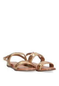 Sandalias de color dorado con tiras trenzadas, suela plana y correa ajustable en el tobillo. El material parece suave con un acabado brillante.