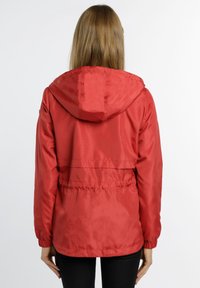 Roter leichter Anorak mit Kapuze, elastischen Bündchen und tailliertem Schnitt. Glattes, wasserabweisendes Material mit einem belüfteten Rückendesign.