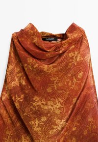 Écharpe couleur rouille en tissu doux, ornée d'un motif floral et de feuillage complexe. Le design présente des textures variées et un subtil éclat.