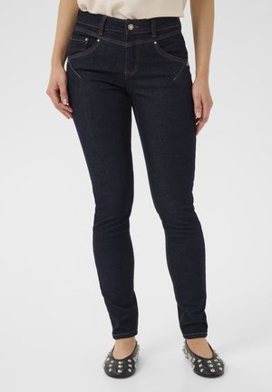 Temno modre slim-fit kavbojke z visokim pasom, z diskretno zlato izbito nitjo in gumbom za zapiranje. Imajo dva sprednja žepa in gladko teksturo.