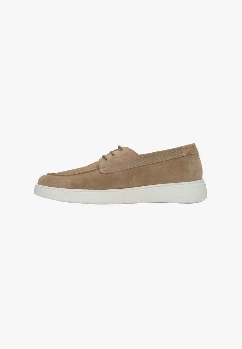 Suede slip-on shoe in beige with a soft texture, featuring a round toe and white rubber sole. Three eyelets for lacing at the front.