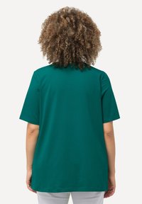 T-shirt in cotone teal con una vestibilità comoda e maniche corte, caratterizzato da un colletto arrotondato e una texture liscia. Vista da dietro.