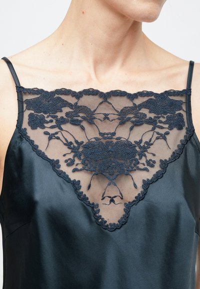 Fekete szatén camisole mély V-alakú nyakkivágással, részletes sötét csipkedíszítéssel. Vékony állítható pántokkal és sima textúrával.