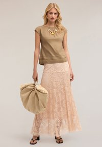 Beige top with cap sleeves, layered pleat detail; pink lace maxi skirt, floral pattern; large beige bag with fur trim; black heeled sandals.