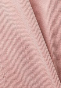 Tissu en velours côtelé rose doux avec des rainures verticales visibles et de légers plis montrant la texture et les détails du matériau.