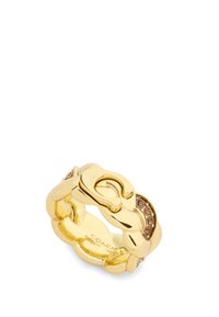 Złoty pierścionek z zaplecionym wzorem ogniw łańcucha, wzbogacony małymi brązowymi kamieniami oraz gładkim, lustrzanym wykończeniem. Wewnątrz wygrawerowane "COACH".