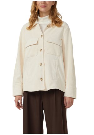 Crème corduroy jas met twee borstzakken, knopen aan de voorkant en lange mouwen, gecombineerd met een bruine broek met wijde pijpen. Gestructeerde stof.