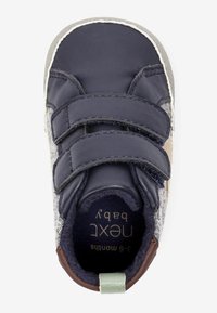 Námořnické kožené boty pro miminka s šedými plstěnými stranami, dvojnásobným suchým zipem a hnědými akcenty. Velikostní štítek uvnitř zní "3-6 měsíců".