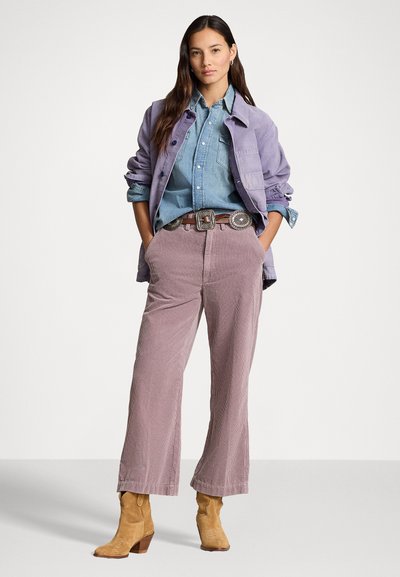Light purple corduroy jacket over a blue denim shirt. Light pink corduroy wide-leg pants and tan heeled ankle boots. Silver belt buckle detail.