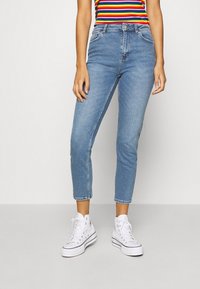 Ljusblå denimjeans med slim fit och cropped längd, med framfickor och en klassisk midja. Tillsammans med vita hög-topp sneakers.