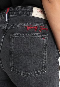 Černé džíny z denimu s červenou výšivkou "Tommy Jeans" na zadní kapse a značkovou etiketu na pase. Standardní design s pěti kapsami.