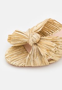 Gullfarget rynket sandal med en stor sløyfe detalj foran, med en glatt, nude innside og et rundt tådesign.