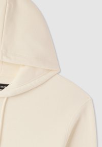 Felpa crema con cappuccio grande, realizzata in tessuto morbido e con dettagli di cucitura visibili. Il design è semplice e privo di motivi o dettagli decorativi.