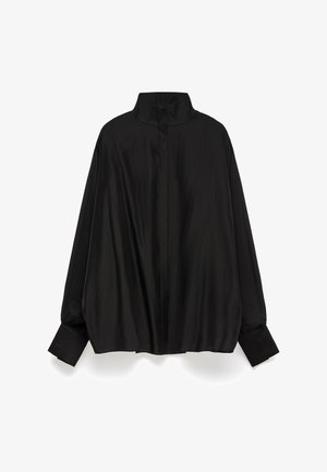 Czarna bluzka z wysokim kołnierzem, długimi rękawami i zapięciem na guziki przy mankietach. Wykonana z gładkiego, lśniącego materiału, o luźnym kroju i szwie z tyłu.