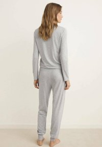 Top de manga larga gris y pantalones a juego en tela suave. El diseño de corte relajado cuenta con una cinturilla cómoda y puños ajustados.