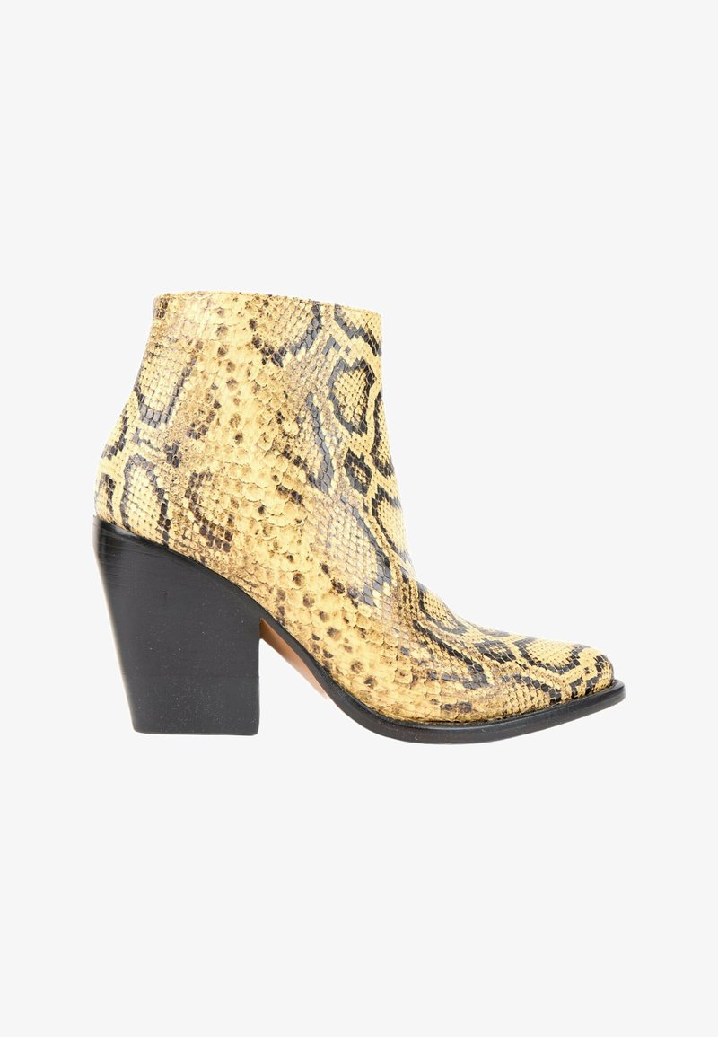 Botte femme hauteur cheville avec motif peau de serpent jaune et noir et talon carré noir, vue de côté sur fond blanc.