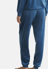 Blauwe velours joggingbroek met elastische boorden en tailleband. Zachte textuur, gladde afwerking en een relaxte pasvorm, die comfort en draagbaarheid benadrukken.