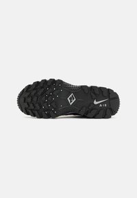 Black athletic shoe sole featuring a textured design, deep treads for grip, and a visible Nike Air logo at the heel.