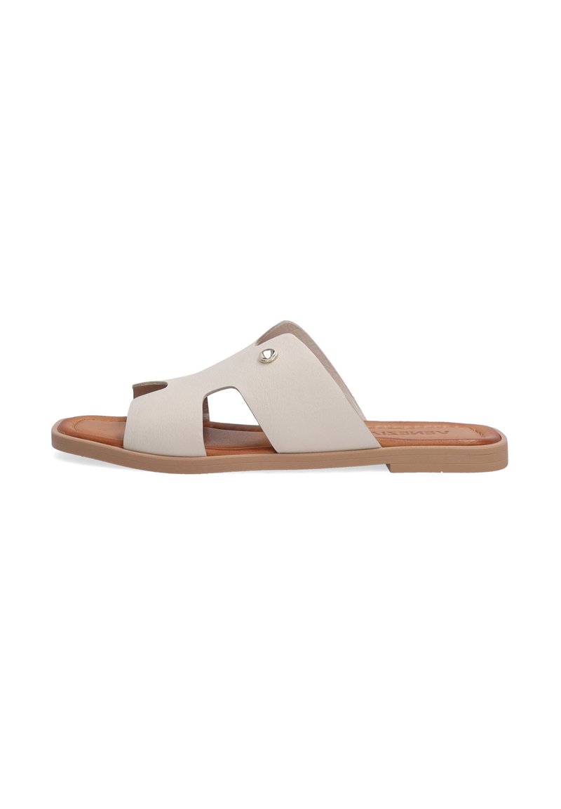 Beige slide sandal med udskæringsdesign, blød syntetisk overdel og brun sål. Har en metalaccent nær buen for detaljer.