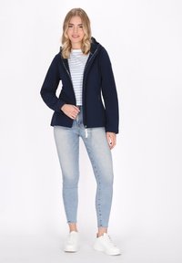 Mornarska zip-up jakna s kapuljačom, bijela prugasta majica, svijetloplave uske traperice i bijele tenisice, koje se odlikuju uskim krojem i glatkom teksturom.