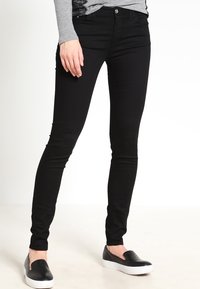 Černé úzké džíny s středním pasem, s předním zapínáním na knoflík, pěti kapsami a hladkým, pružným materiálem.