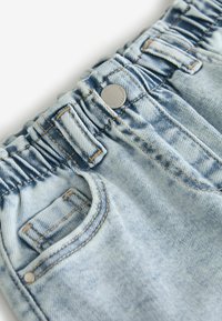 Ceinture de jean en denim bleu clair avec élastique froncé, bouton en métal, passants de ceinture et poche avant avec détail de couture rivetée.
