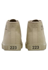 Beżowe trampki typu high-top z płótna o teksturowanej powierzchni, okrągłym nosku i gumowej podeszwie. Posiadają czarne nadrukowane logo i liczby po bokach.