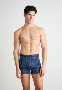 Tengerészkék boxer alsónadrág elasztikus anyagból, kopott katonai mintával, és egy egyszínű derekú részen "BJÖRN BORG" logóval.