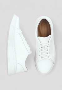 Białe skórzane sneakersy o gładkiej fakturze, okrągłym nosku i niskoprofilowej gumowej podeszwie. Posiadają płaskie sznurowadła i subtelne detale przeszycia.