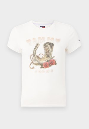 Biała bawełniana koszulka z grafiką przedstawiającą podkowę, kowbojskie buty i róże, z napisem "TOMMY JEANS" na dole.