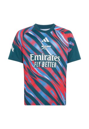 Dreng holder en rød Arsenal-fodbold, iført en Arsenal-trøje med Emirates Fly Better-logo og hvide shorts med røde kanter.