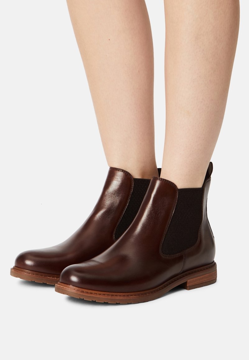 Bruna läder Chelsea-boots med elastiska sidopaneler, rund tå och låg staplad klack. Slät yta med texturerade accenter.