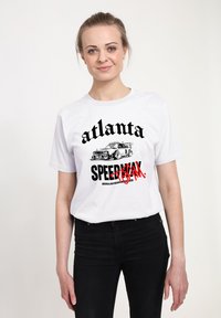 Bílý bavlněný tričko s černým textem "atlanta" a "SPEEDMAX" s červeným přeškrtnutím, vedle grafiky designu auta.