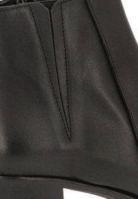 Botín negro de cuero a la altura del tobillo con textura suave, forma tapered y sutiles detalles de costura. Incluye un tacón bajo y apilado.