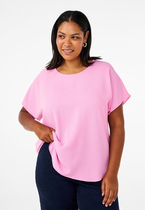 Svetloružová blúzka s krátkym rukávom a zaobleným výstrihom s jemnou textúrou. Kombinovaná s tmavomodrými džínsami, ktoré majú voľný strih a bočné vrecká.