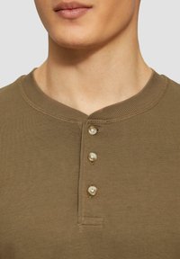 Maglietta henley in cotone verde oliva con scollo a coste testurizzato e patta con tre bottoni, dotata di bottoni color naturale.