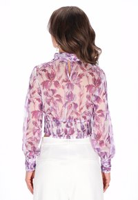 Doorzichtige bloemenblouse in lichtpaarse en roze tinten, met lange pofmouwen, een gerimpelde tailleband en een keyhole sluiting aan de achterkant.