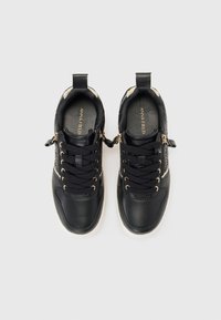 Schwarze Sneaker mit strukturiertem Finish, goldenen Hardware-Akzenten, Schnürung auf der Vorderseite und einem Reißverschluss an der Außenseite. Mit einer leichten Sohle.