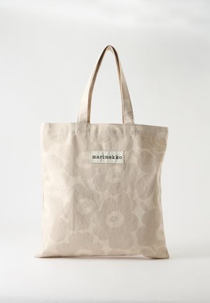 Sac fourre-tout en tissu beige avec un motif floral discret et une étiquette "marimekko" centrée sous les anses sur un fond uni.