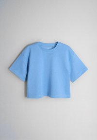 T-shirt court uni bleu clair à manches courtes avec un col rond, présenté sur un fond gris uni.