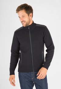 Sweater zippé marine avec un col haut, doté d'accents gris aux épaules, de poignets côtelés et de poches latérales. Texture tricot lisse.