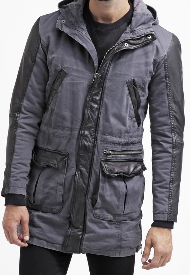 Herrgrå parkas med huva, med svarta läderdetaljer, dragkedjefickor och en strukturerad tygfinish. Långärmade med ribbade ärmslut.